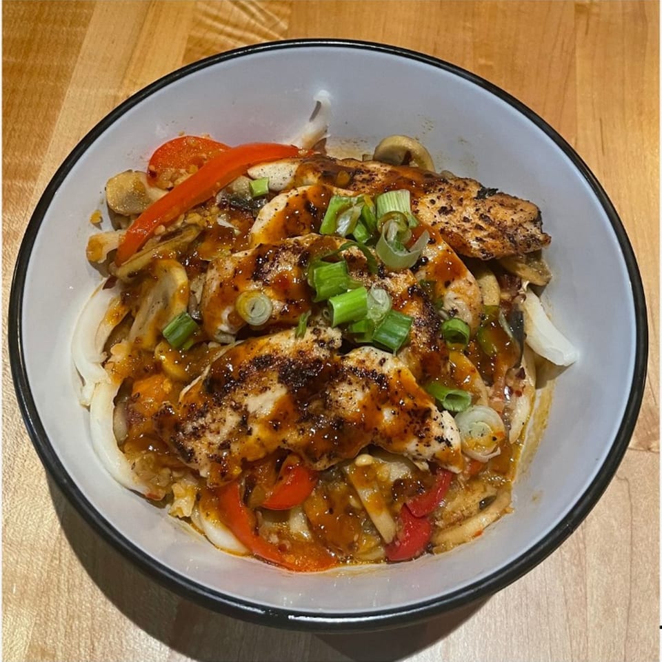 NAGS Bar and Kitchen's grilled chicken with red peppers, mushrooms, onions, and scallions in a bowl.